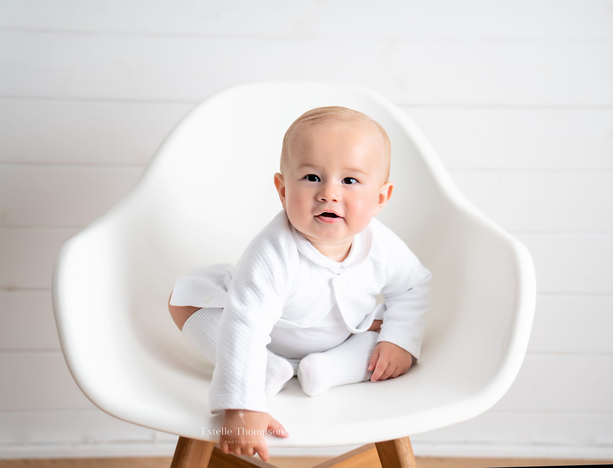 Baby sitting on a white chair in a sevenoaks photography studio