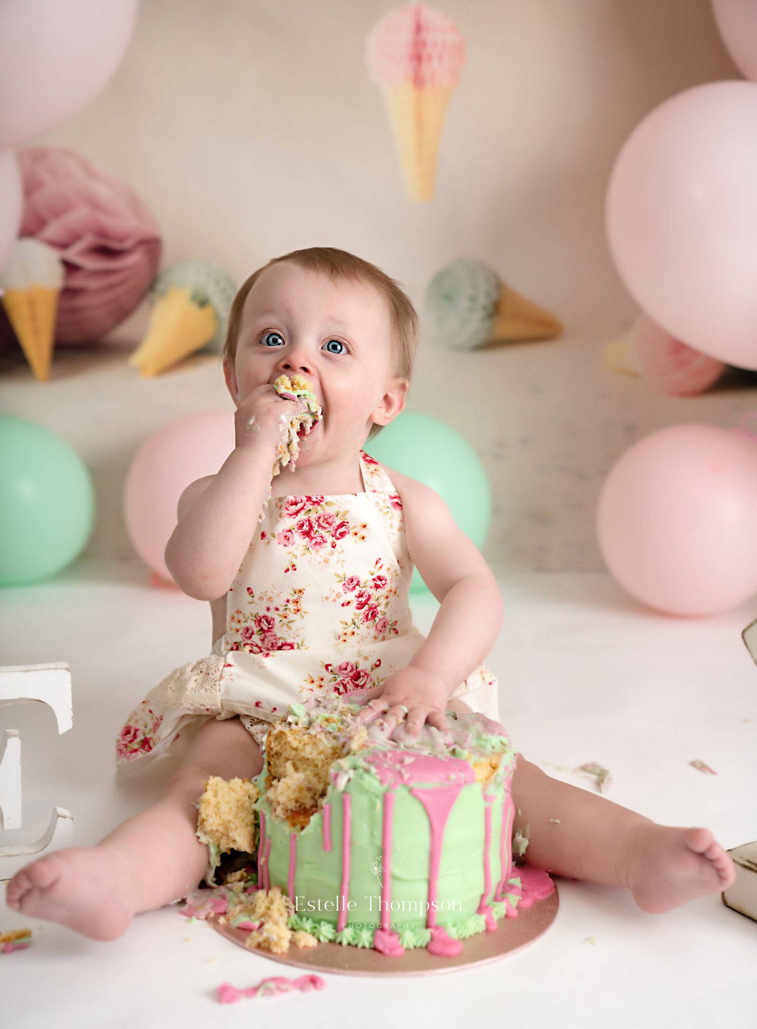 A little girl is putting lots of cake in her mouth at a cake smash photoshoot in Longfield Kent