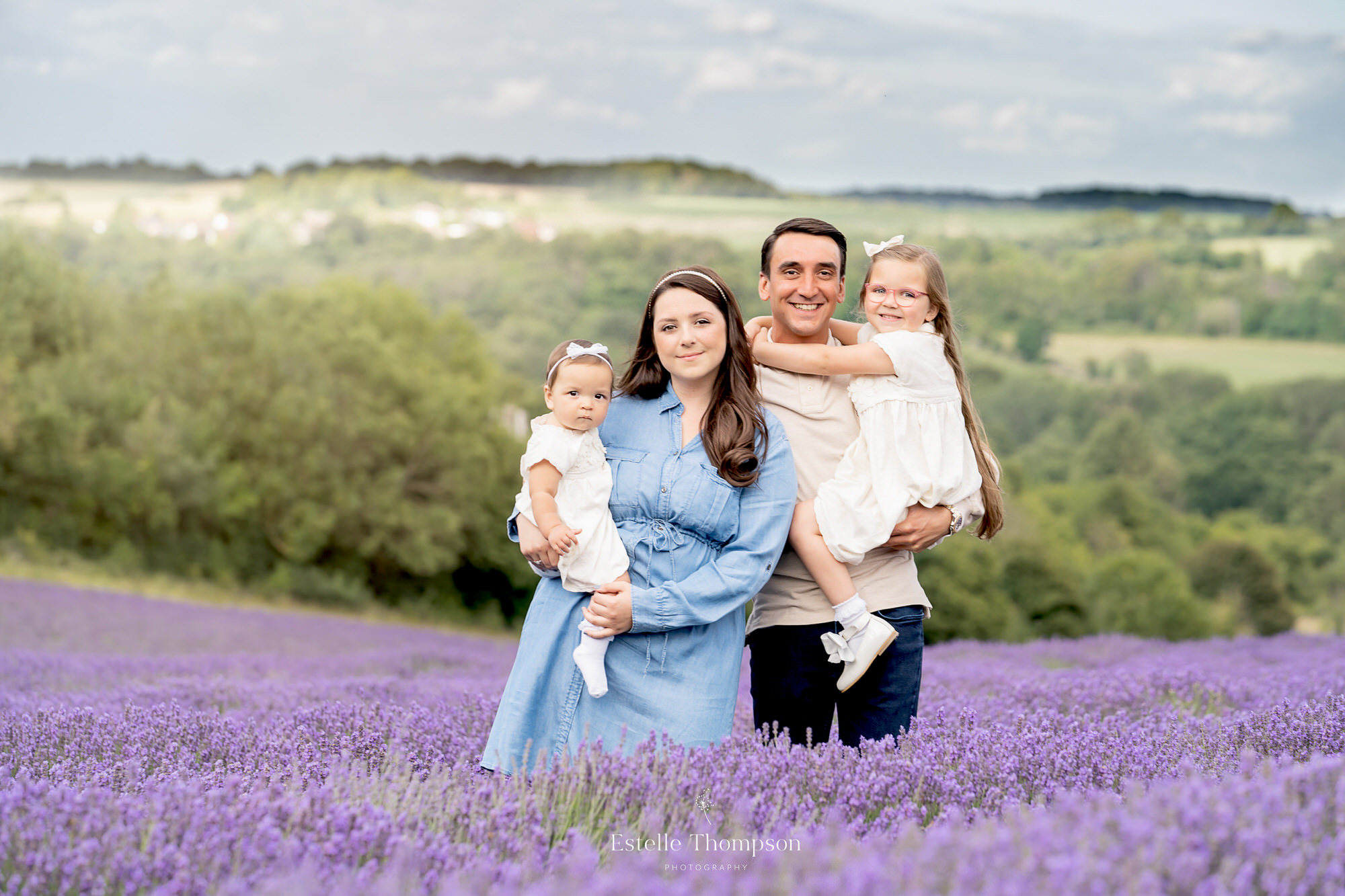 A mum a Dad and their two daughters stand in a lavender field in Sevenoaks for a family photoshoot
