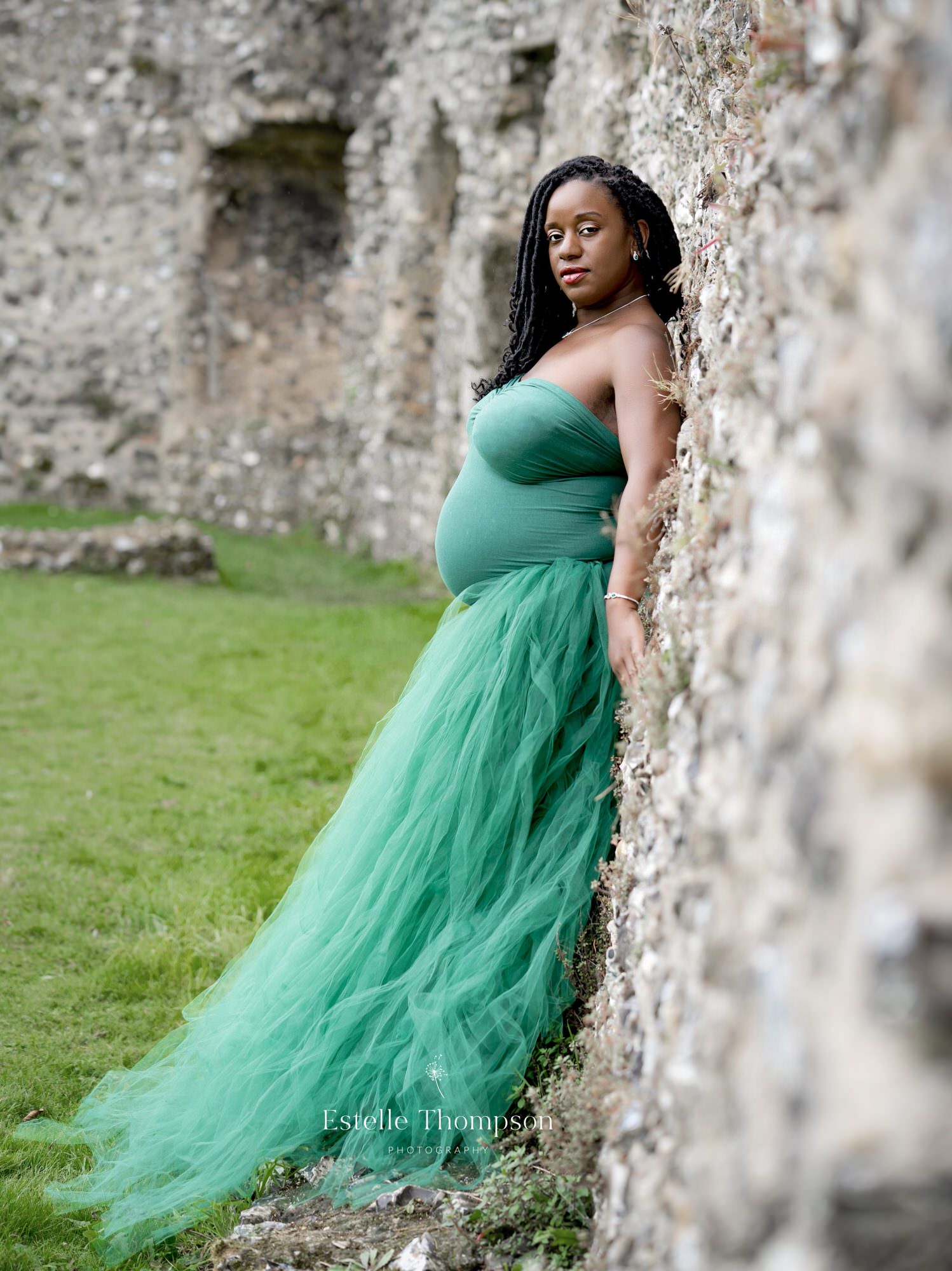 A pregnant lady leans against a castle wall by Kent maternity photographer