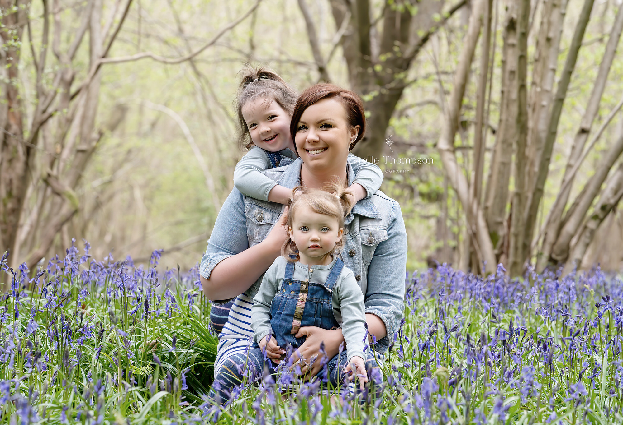 A mum and her two daughters in a bluebell wood by sevenoaks family photographer