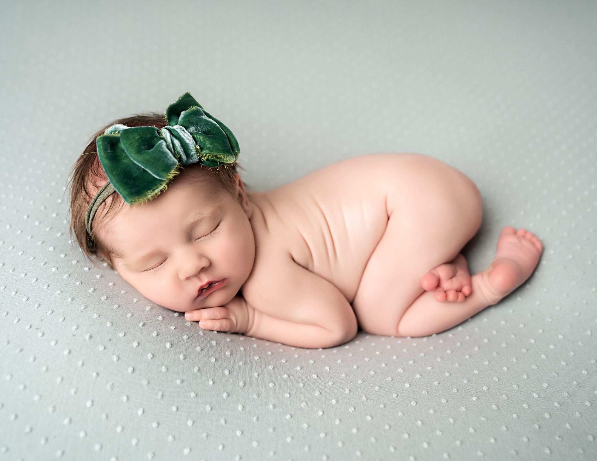 newborn baby girl laying on a green blanket