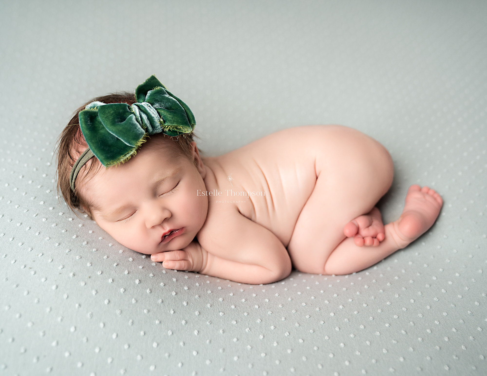 newborn baby laying on a green blanket