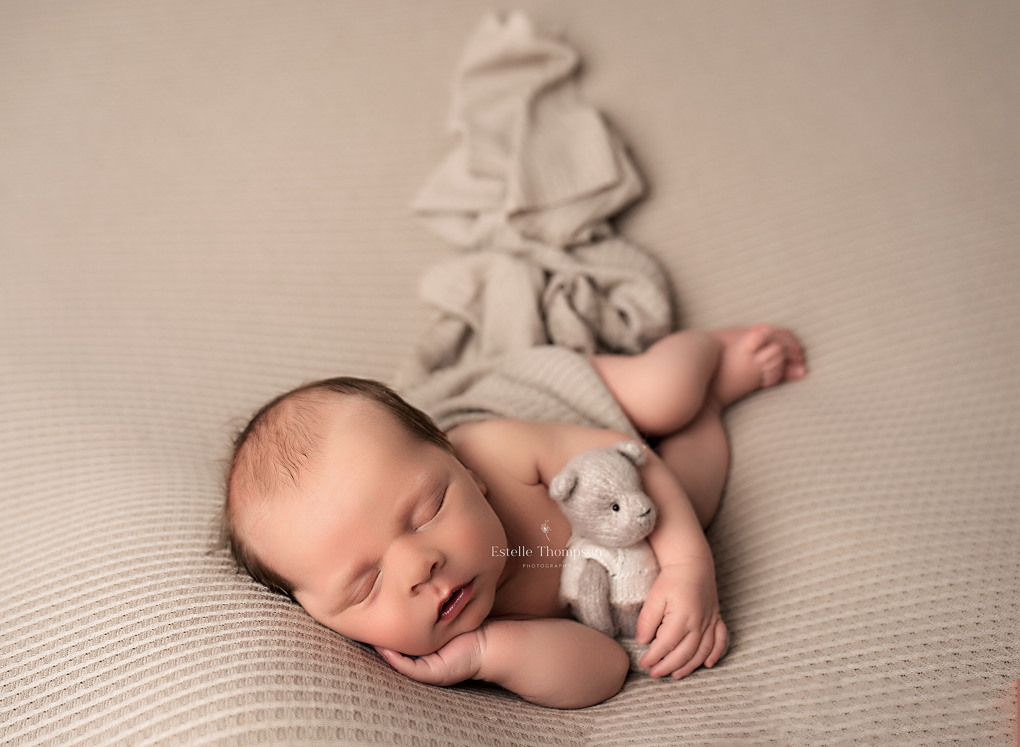 Newborn baby girl laying on a tiny wooden bed