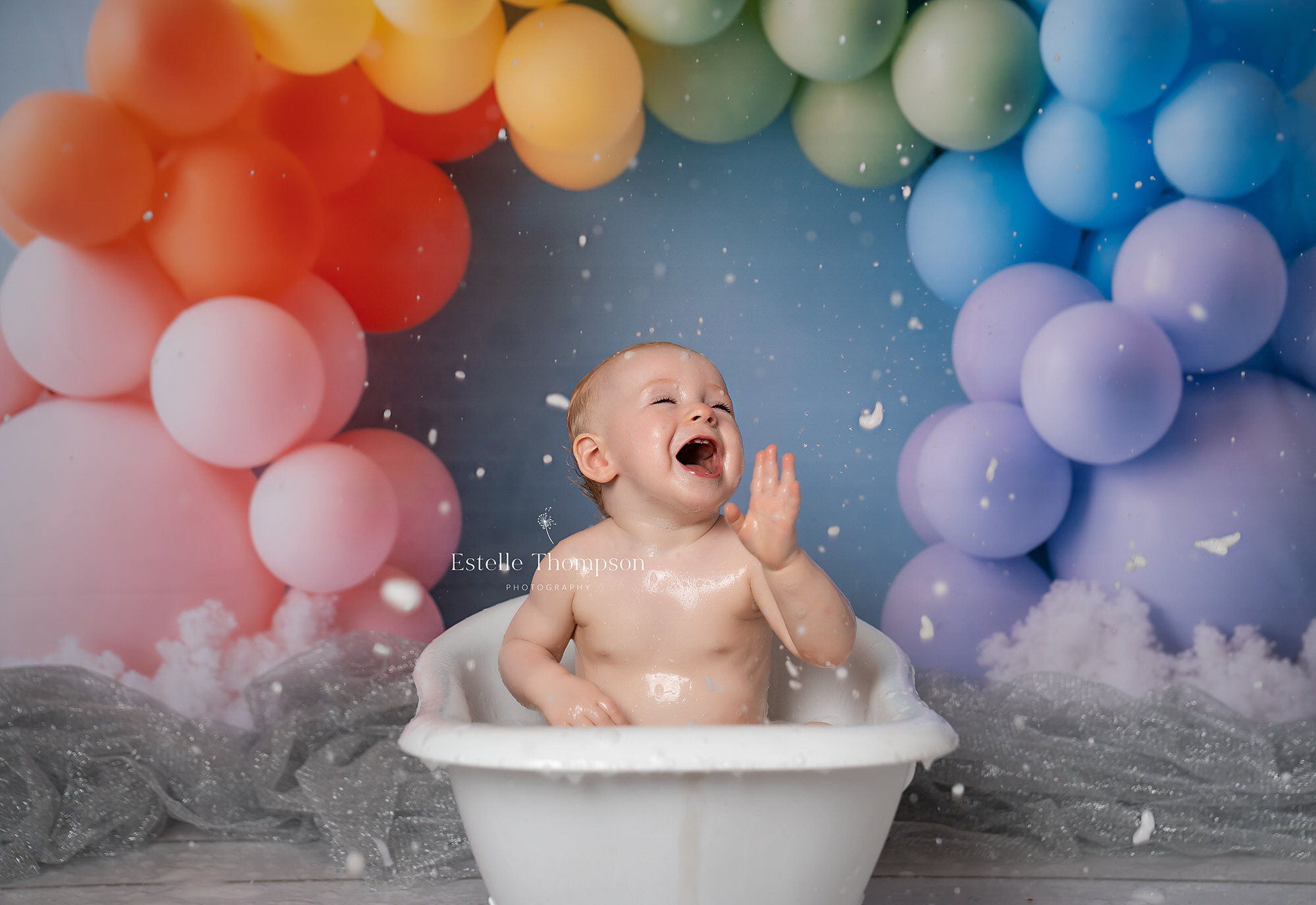 Baby girl splashing in the bath tub after her cake smash photoshoot